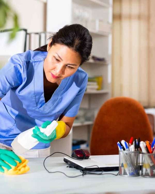 image_02_services Professional cleaner from Aloha Maids disinfecting desk and office surfaces as part of detailed cleaning services.