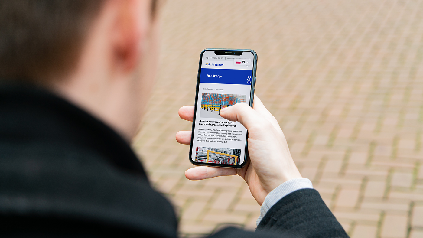 Zdjęcie przedstawia człowieka korzystającego z telefonu na którym jest wyswietlana strona Anter System