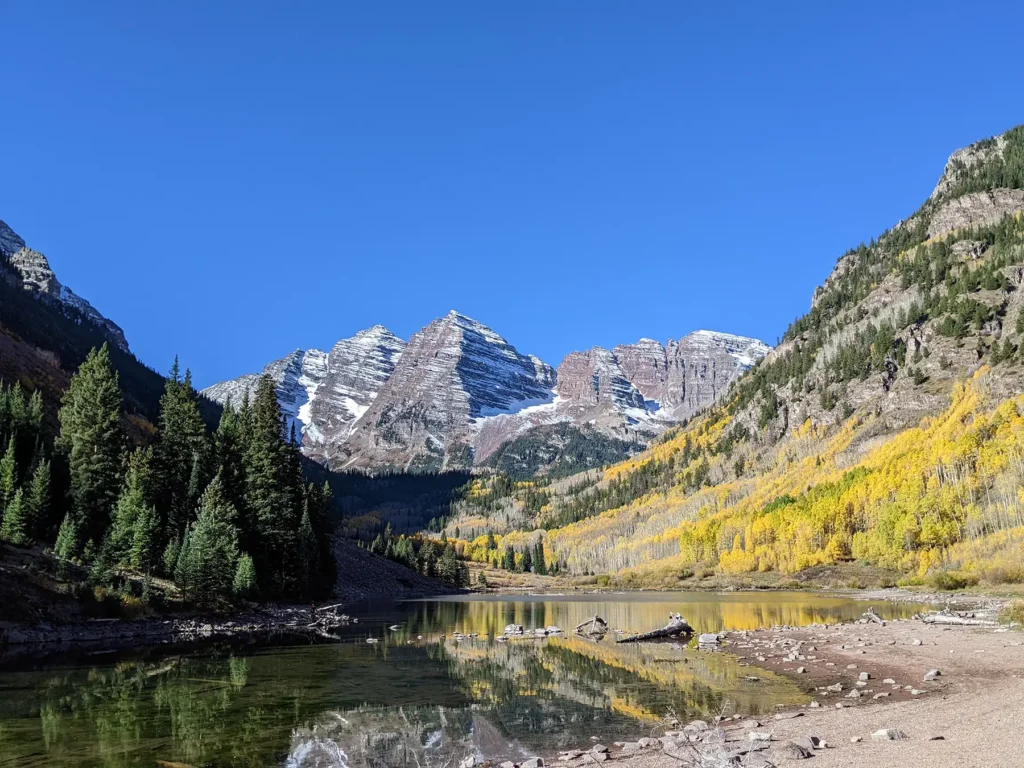 A wide shot of a mountain range surrounded by pine trees on a sunny day.
