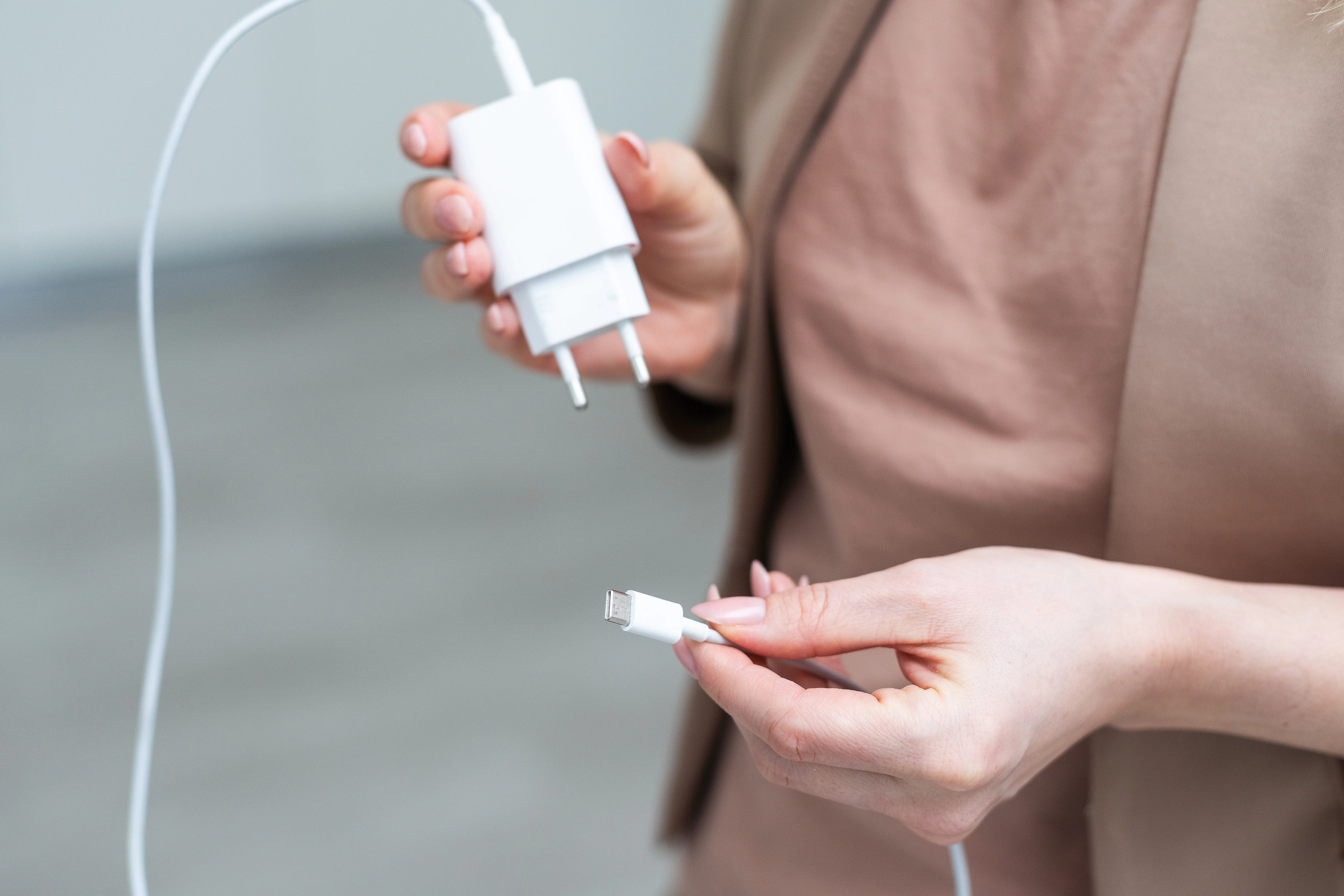 person holding a charging adaptor and cord.