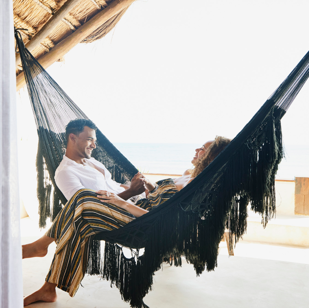 Smiling couple relaxes together in a black hammock.