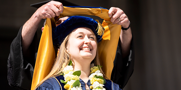 photo of female student being hooded at commencement