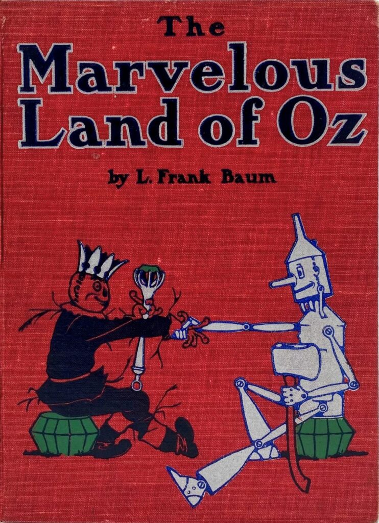 A mostly red cover featuring the Scarecrow and Tin Man shaking hands. The text reads: The Marvelous Land of Oz by L. Frank Baum.