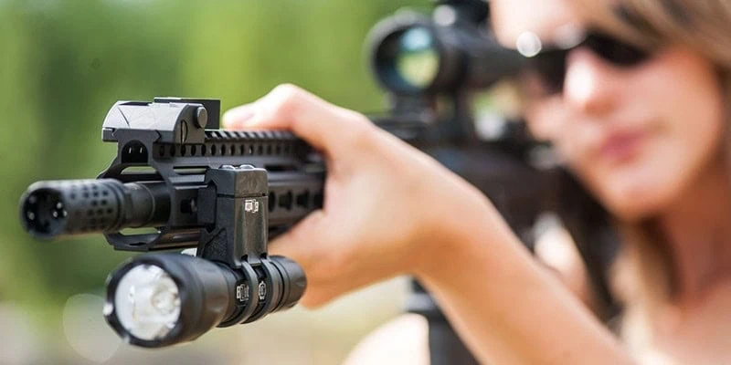 Woman Aiming Rifle with Elzetta Flashlight Mounted on it with ZRX Flashlight