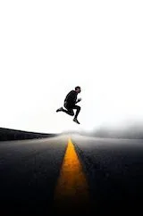 A person jumps over a cone.