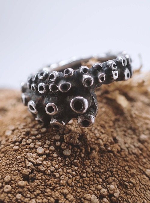 black silver ring in form of an octopus tentacle placed on a stone