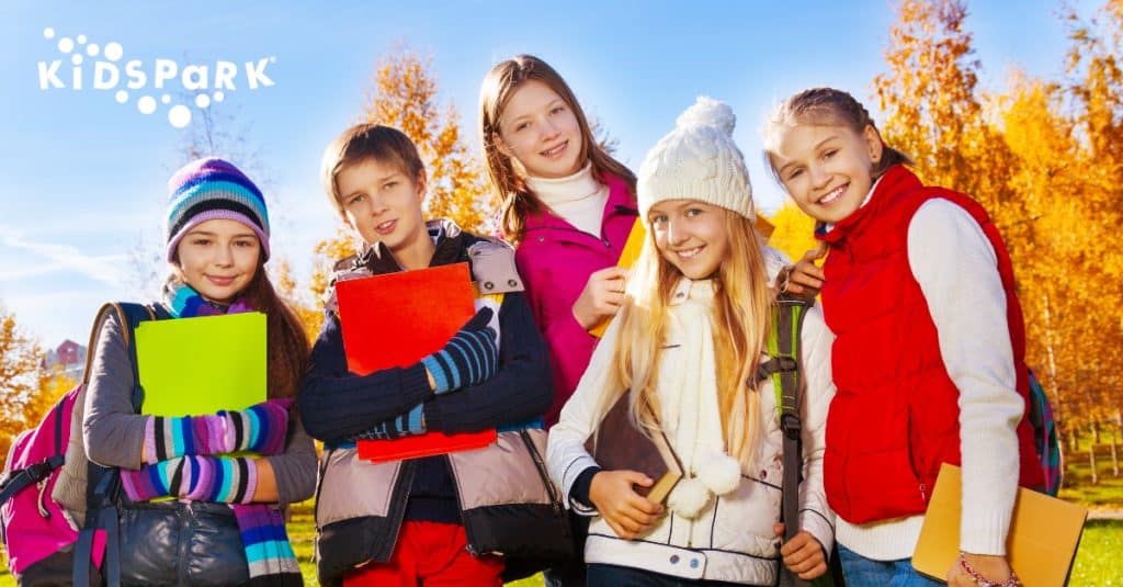 A group of five kids in warm clothes outside at Kidspark in San Jose, California, highlighting childcare options for parents over the holidays.