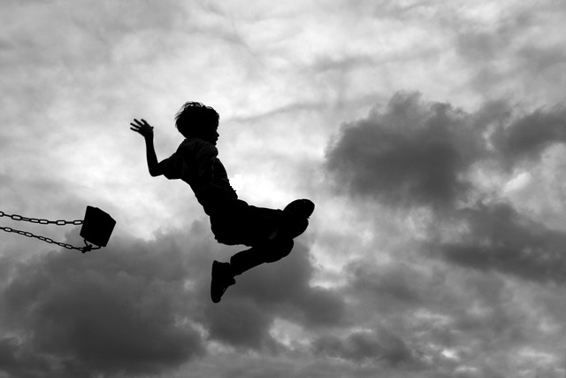 Silhouette Of Little Boy Jumping Off Swing