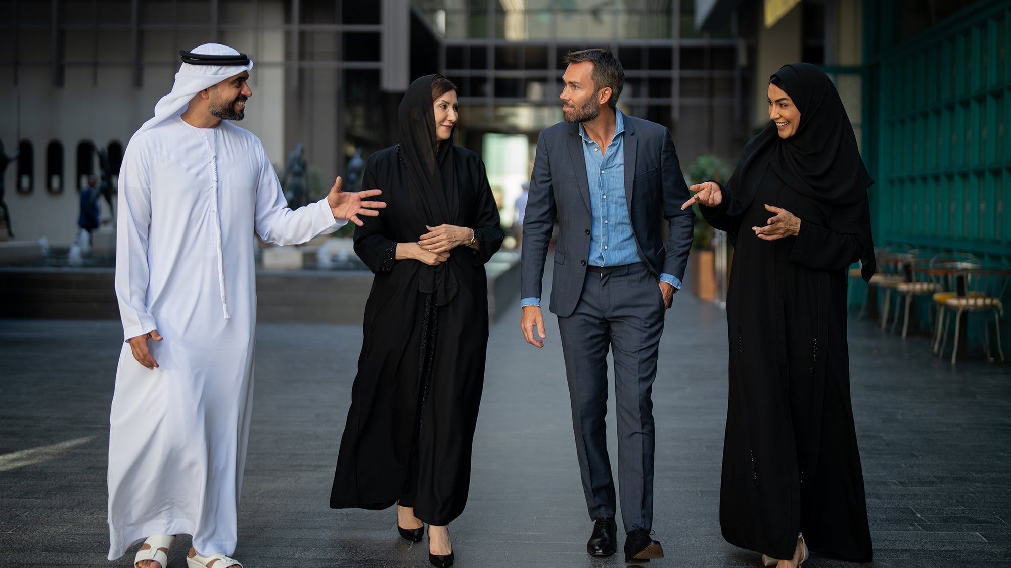 A group of people are walking and talking in different kinds of dress.