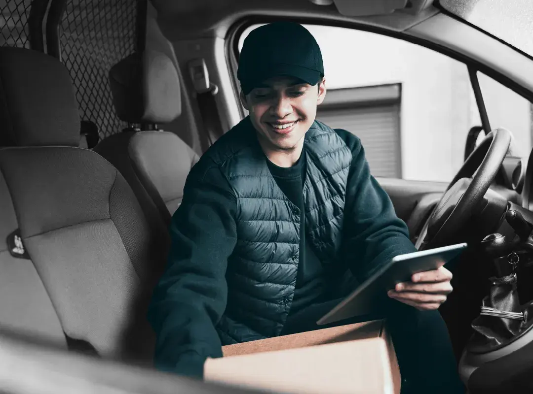 A carrier reviews a delivery on a tablet inside a delivery van