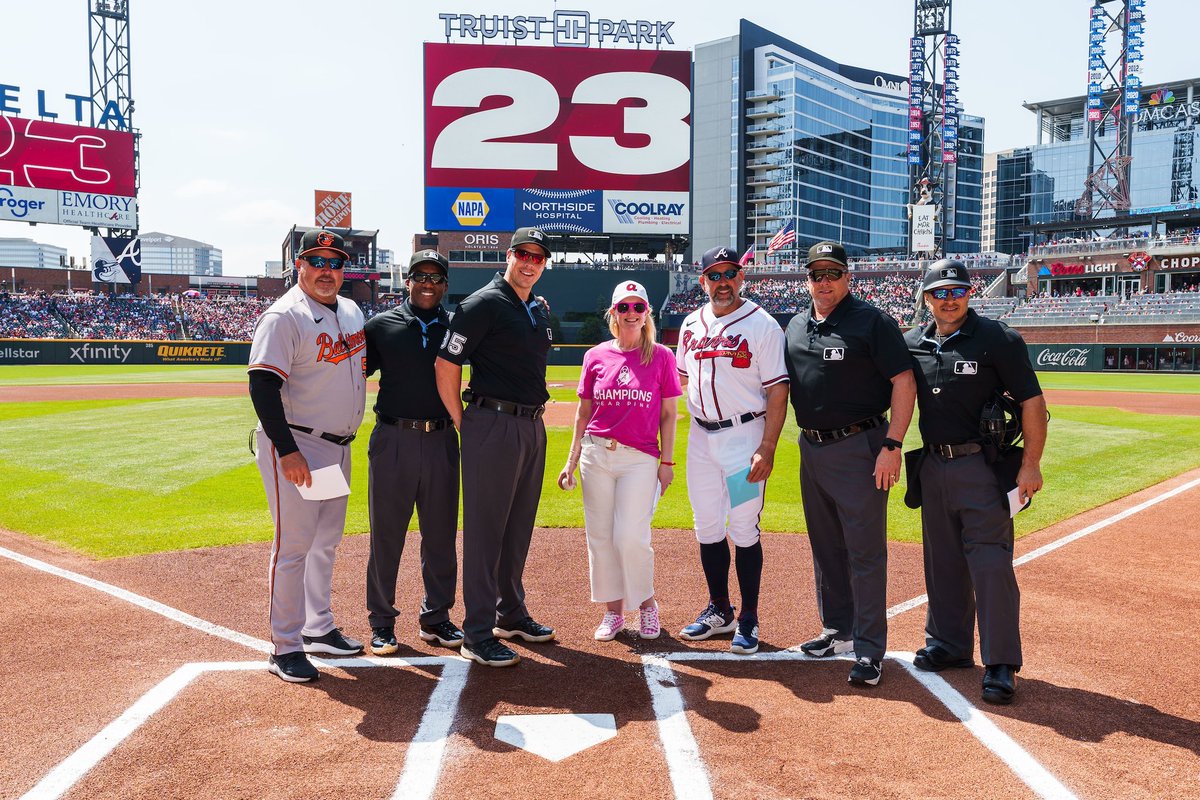 breast cancer survivor with coaches and umpires at home plate for lineup card exchange