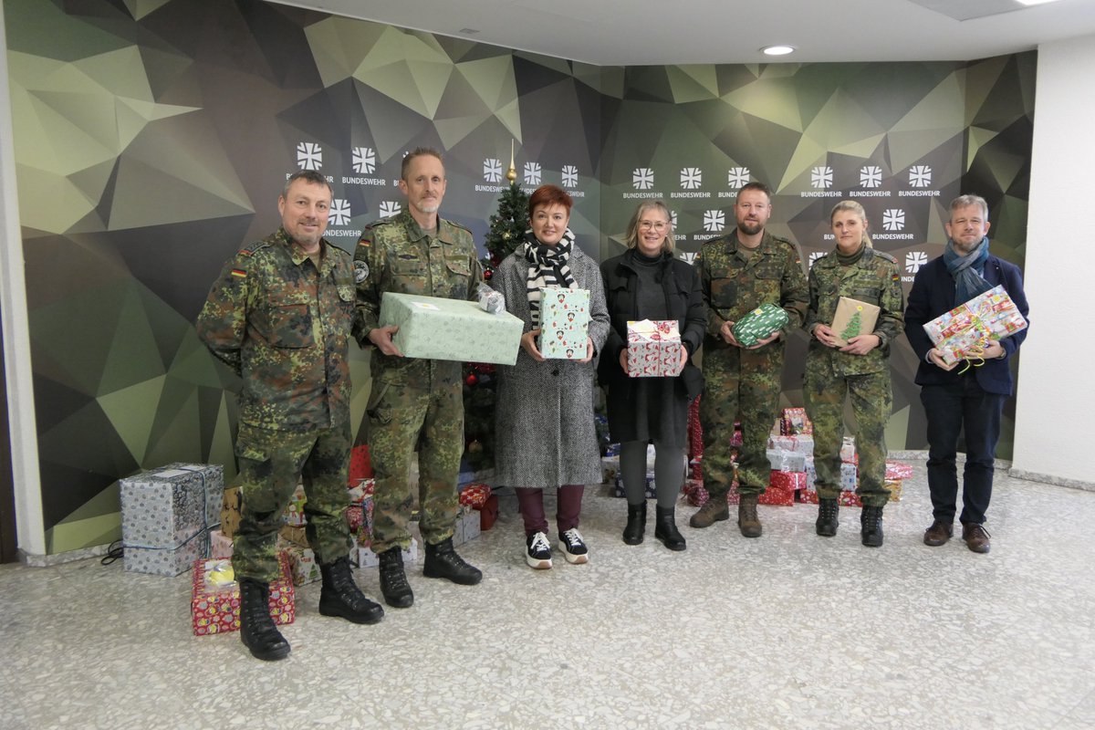 Eine Gruppe Soldatinnen und Soldaten steht mit Geschenken vor einem Bundeswehr-Aufsteller.