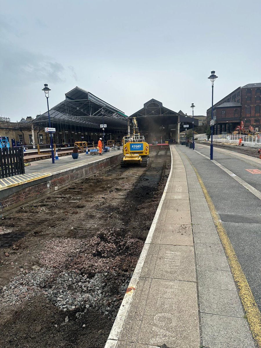 Platform view showing where the tracks have been removed. Large yellow digger in the background.