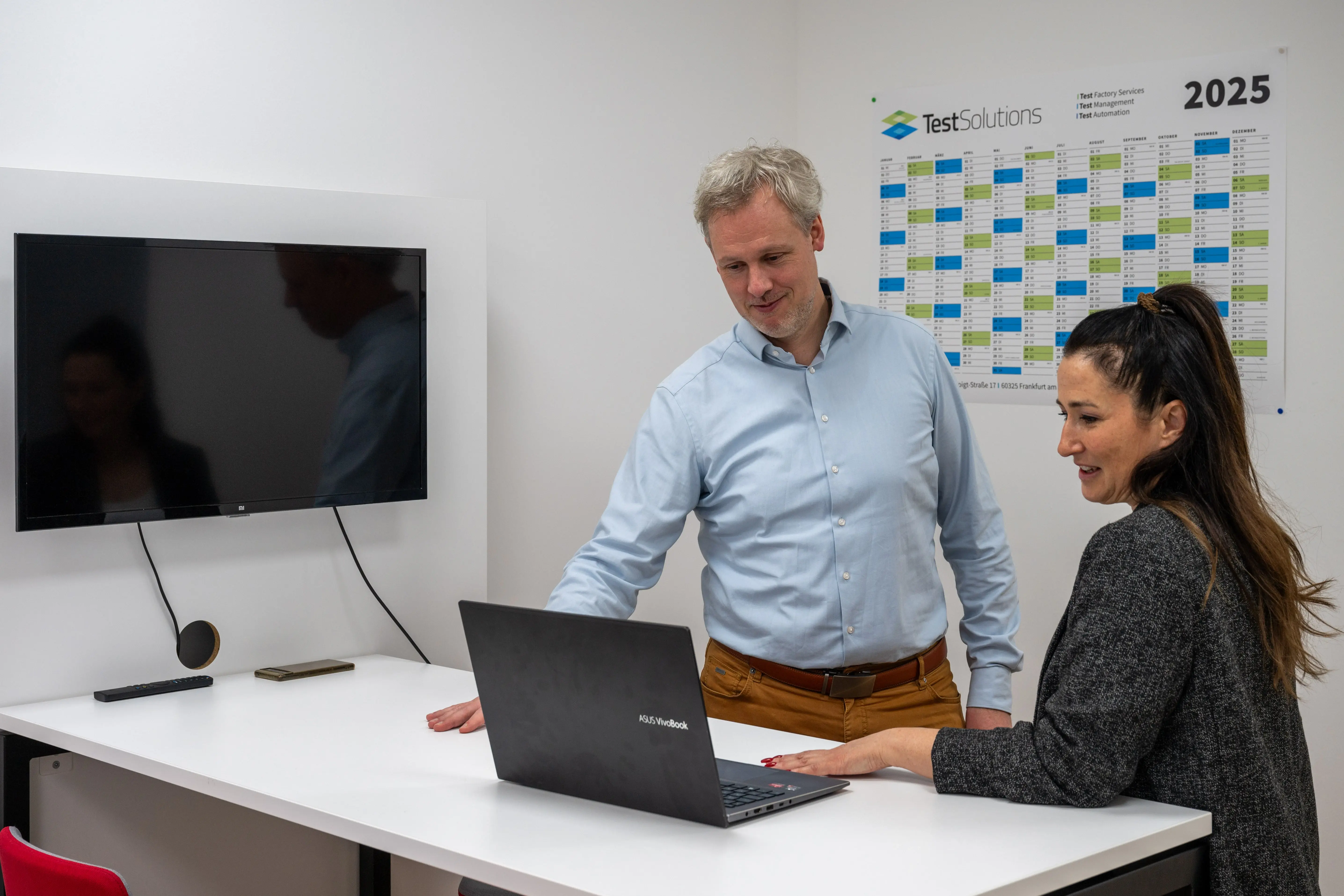 Zwei Personen besprechen etwas am Laptop in einem Büro