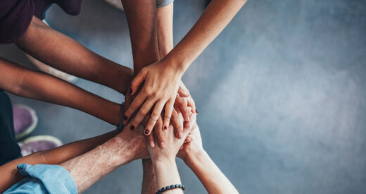 Close up top view of young people putting their hands together. Friends with stack of hands showing unity.