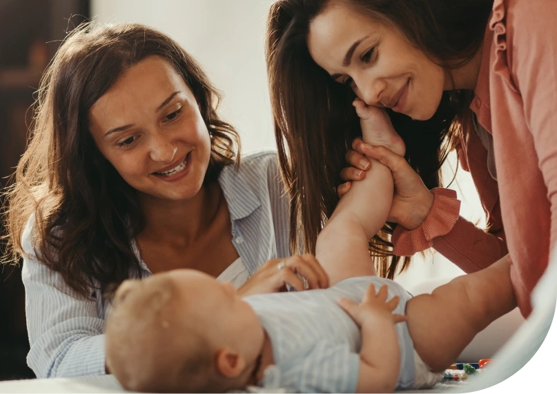 Two women smiling at a baby