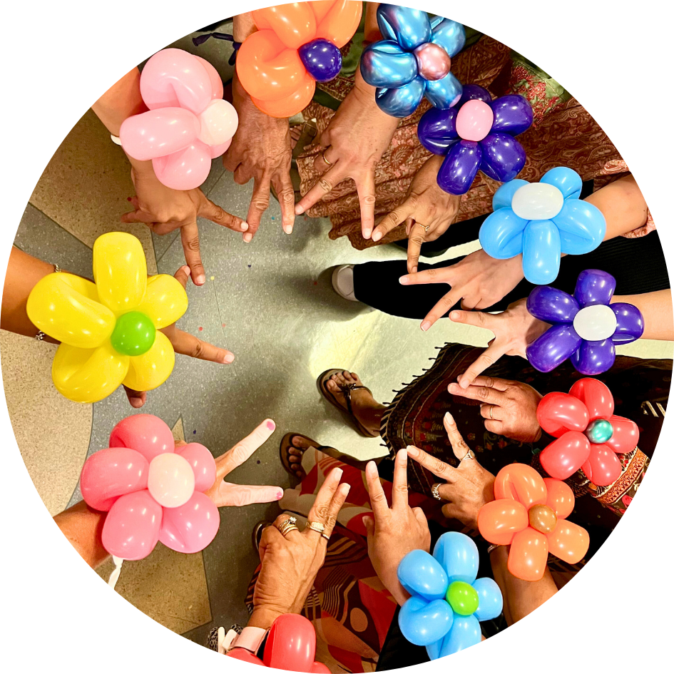 Adults wear colourful flower balloons on their wrists, made by Hyper the Clown.