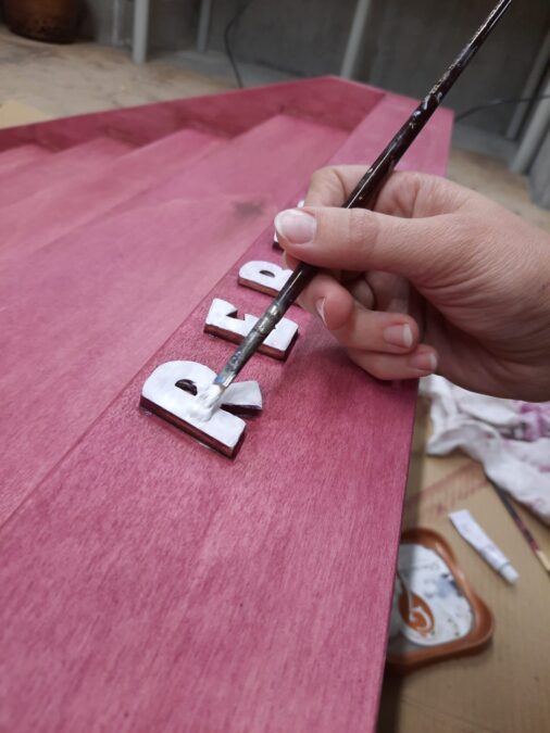 Painting the letters white on the Montessori bookshelf