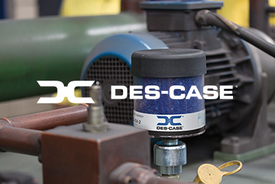 logo_Des-Case_400x267 The Des-Case logo in white with machinery in the background.